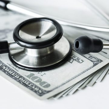 Closeup of cash and a stethoscope healthcare and expenses concept